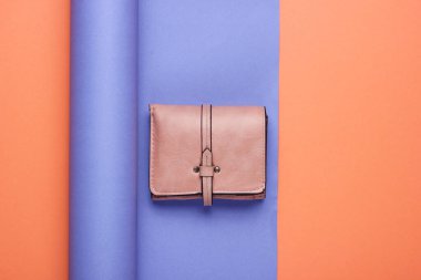 Deri cüzdan sarılı kağıt arkaplanda. Renkli trend, minimalist moda natürmort hayat. Üst görünüm