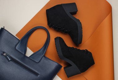 Katlanmış kağıt arka planda siyah süet botlar ve deri çanta. Minimalist moda hala hayattadır. Düz yatıyordu. Üst görünüm