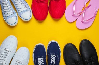 Sarı arka planda bir sürü ayakkabı var. Minimalist moda konsepti. Üst Manzara. Boşluğu kopyala