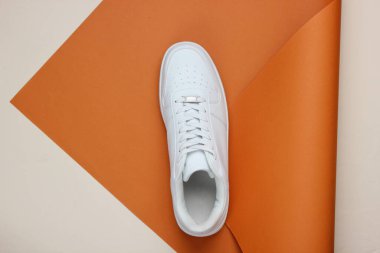 Katlanmış kağıttan arka planda şık beyaz ayakkabılar. Minimalizm moda kavramı. Üst görünüm