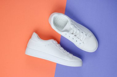 İki renkli kağıttan arka planda beyaz moda ayakkabılar. Üst görünüm