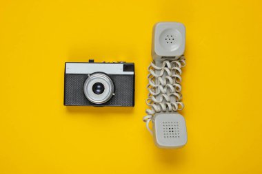 Modası geçmiş bir telefon, sarı arka planda retro kamera. Üst görünüm