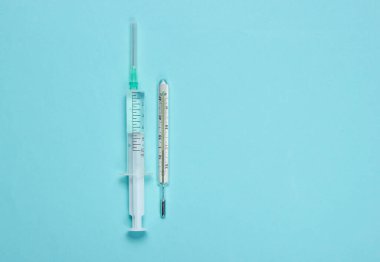 Mavi arka planda tıbbi hayat. Şırınga, termometre. Minimalizm