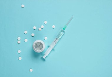 Mavi arka planda tıbbi hayat. Şırınga, şişe hapları. Minimalizm. Üst görünüm