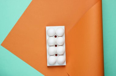 Renkli arka planda beyaz tavuk yumurtası tepsisi. Minimalist gıda konsepti. Üst görünüm