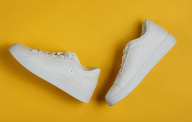 Sarı arka planda şık beyaz ayakkabılar. Üst görünüm