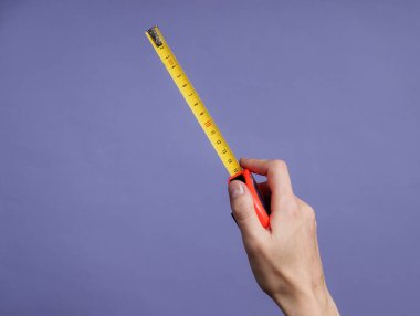 Kadın elleri mor arka planda endüstriyel mezura ile ölçümler yapar