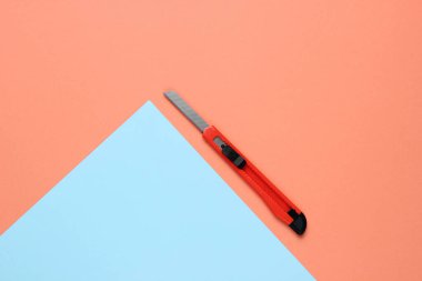 Renkli arka planda kağıt kesmek için kırtasiye bıçağı. Üst görünüm