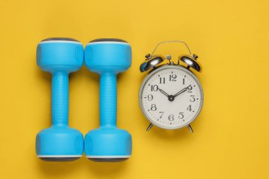 Eğitim zamanı! Salak, sarı arka plandaki çalar saat. Minimalist spor konsepti. Üst görünüm