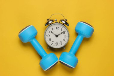 Eğitim zamanı! Salak, sarı arka plandaki çalar saat. Minimalist spor konsepti. Üst görünüm