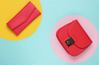 Kırmızı deri çanta ve mavi arka planda renkli daireler olan cüzdan. Üst Manzara. Minimalist moda konsepti.