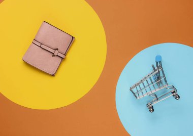 Minimalizm alışveriş konsepti. Alışveriş arabası, arka planda deri cüzdan.