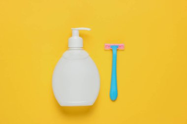 Tüy dökümü için bir şişe jöle, sarı kağıtta jilet. Pastel renk eğilimi. Minimalist güzellik konsepti. Üst görünüm