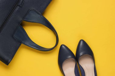 Klasik yüksek topuklu ayakkabılar, sarı arka planda deri çanta. Minimalizm moda kavramı. Üst görünüm