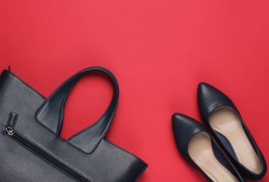 Klasik yüksek topuklu ayakkabılar, kırmızı arka planda deri çanta. Minimalizm moda kavramı. Üst görünüm