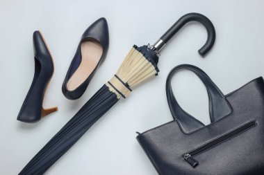 Klasik yüksek topuklu ayakkabı, deri çanta, beyaz arka planda şemsiye. Minimalizm moda kavramı. Üst görünüm