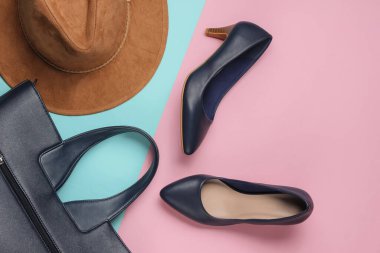Keçeli şapka, yüksek topuklu ayakkabılar, pembe mavi pastel arka planda deri çanta. Minimalist moda konsepti. Üst görünüm