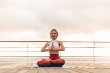 Gün doğumunda yoga antrenmanı. Genç Yogi kadın, sabah namaste ile sahilde poz veriyor.