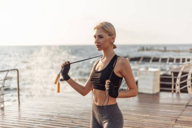 Bandajlı elleri olan ve sahilde poz veren sporcu kadın kickboksör..