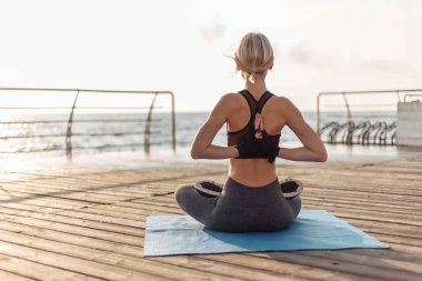 Gün doğumunda yoga antrenmanı. Genç bayan yogi gün doğumunda plajın arkasında Namaste yapıyor.