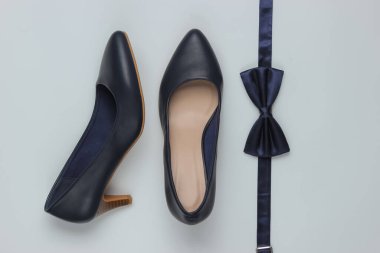 Minimalist moda hala hayattadır. Kadın yüksek topuklu ayakkabıları ve beyaz arka planda papyon. Üst görünüm