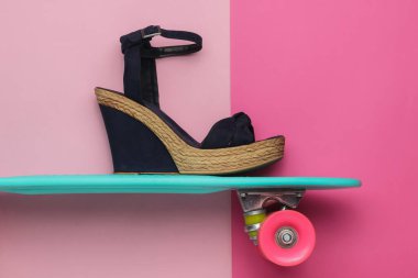 Yaz eğlencesi. Pembe stüdyo arka planında kruvazör tahtasıyla platformda kadın sandaletleri. Moda çekimi, üst manzara.