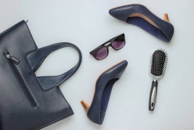 Düz kadın ayakkabıları, beyaz arka planda aksesuarlar. Çanta, yüksek topuklu ayakkabı, güneş gözlüğü, tarak. Üst görünüm