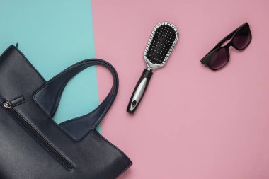 Pembe arka planda yassı kadın aksesuarları vardı. Çanta, güneş gözlüğü, tarak. Üst görünüm