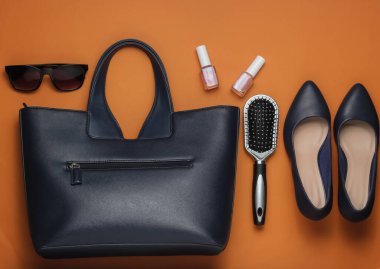 Çantada ne var? Kadın aksesuarları, kahverengi arka planda ayakkabılar. Üst görünüm, minimalizm