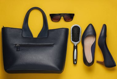 Sarı arka planda düz stil kadın aksesuarları vardı. Çanta, yüksek topuklu ayakkabı, güneş gözlüğü, tarak. Üst görünüm