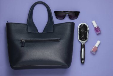 Çantada ne var? Mor arka planda kadın aksesuarları. Üst görünüm, minimalizm
