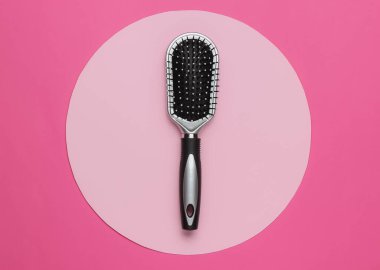 Pembe arka planda güzel bir saç fırçası, daire şeklinde. Kadın Saç Bakımı Aksesuarları.