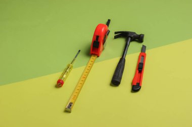 Yeşil arka planda çekiç, tornavida, bıçak ve cetvel. Minimalizm