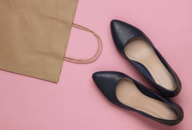 Alışveriş konsepti. Moda stüdyosu çekimi. Pembe pastel arka planda alışveriş yapmak için yüksek topuklu ayakkabılar ve kese kağıdı. Üst görünüm