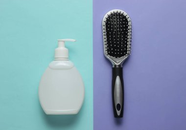 Minimalist güzellik konsepti. Saç bakımı. Mor mavi arka planda tarak ve bir şişe şampuan. Üst görünüm