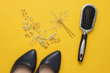 Gelinin ücreti, düğün günü. Gelinin saçında süsleme, tarak, sarı arka planda yüksek topuklu ayakkabılar.