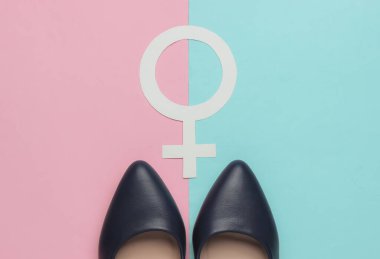 Feminizm. Kadın cinsiyeti sembolü, pembe mavi pastel arka planda yüksek topuklu ayakkabılar. Üst görünüm