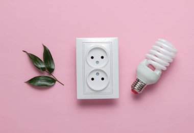 Eko konsepti. Güç Enerji Ekonomisi. Gezegeni kurtar. Çift güç prizi, yeşil yapraklar, pembe pastel arka planda spiral lamba. Stüdyo çekimi