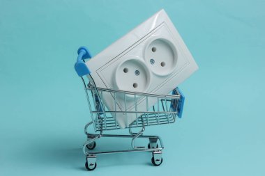 Mavi arka planda çifte elektrik prizi olan alışveriş arabası.