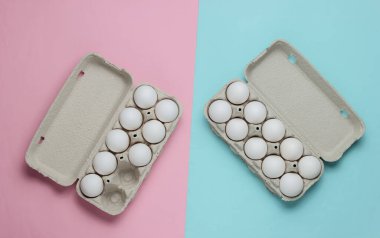 Üzerinde pembe mavi pastel arka planda yumurtalar olan karton tepsiler. Minimalizm aşçılık konsepti. Üst görünüm.