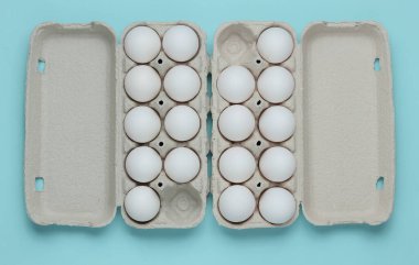 Mavi pastel arka planda yumurtalı karton tepsiler. Minimalizm aşçılık konsepti. Üst görünüm.