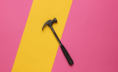 Pembe-sarı kağıt arka planda çekiç. Üst görünüm