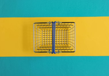 Minimalist alışveriş konsepti. Mavi-sarı arka planda alışveriş sepeti.