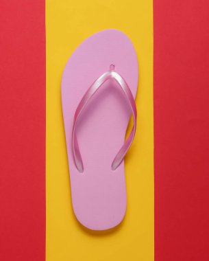 Sarı-kırmızı arka planda pembe parmak arası terlikler. Üst Manzara. Minimalizm.
