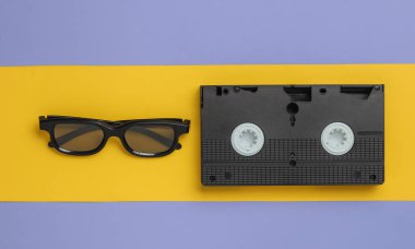 3D gözlükler, sarı-mor arka planda retro video kaset. 80 'ler. Üst görünüm