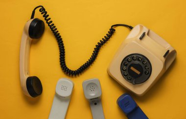 Yardım hattı, ofis kavramı. Eski bir telefon, sarı kağıtta bir sürü cep telefonu. Üst Manzara. Retro biçimi