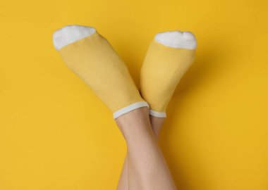 Stüdyonun arka planında sarı çoraplı kadın bacakları. Minimalist moda konsepti. Üst görünüm