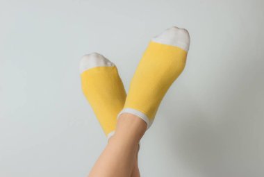 Beyaz arka planda sarı çoraplı kadın ayakları. Üst Manzara. Minimalizm moda kavramı