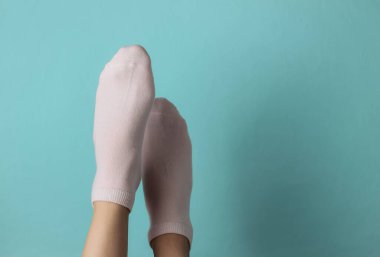 Mavi arka planda pembe çoraplı kadın bacakları. Üst Manzara. Minimalizm moda kavramı