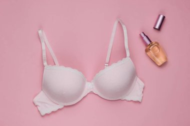 Şık sütyen, pembe pastel arka planda parfüm şişesi. Üst Manzara. Güzellik ve moda minimalist natüralistik hayat
